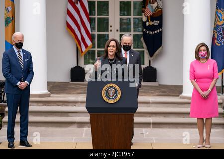 Präsident Joe Biden, der Mehrheitsführer des Senats, Charles „Chuck“ Schumer, D-N.Y., und die Sprecherin des Repräsentantenhauses, Nancy Pelosi, D-Calif., sehen sich an, wie Vizepräsidentin Kamala Harris am Freitag, den 12. März 2021, im Rosengarten des Weißen Hauses Kommentare zum amerikanischen Rettungsplan abgibt. Stockfoto
