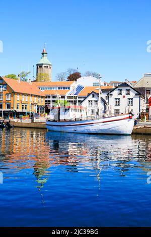 Traditionelles norwegisches Fischerboot, das im Hafen von Stavanger festgemacht ist. Alte Lagerhäuser am Kai sind jetzt trendige Restaurants, Bars und Cafés., Norwegen. In der BA Stockfoto