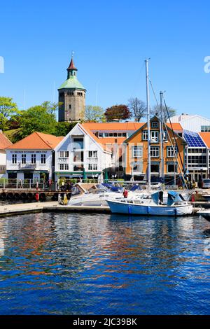 Vor den alten Lagerhäusern am Kai auf Skagerkaien vertäuten Yachten. Dahinter der Wachturm auf dem Hügel. Der Valbergturm, oder Valberget UTS Stockfoto