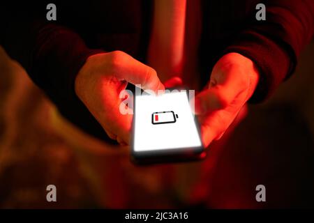 Mann Hände mit Smartphone-Akku schwach aufgeladen Batterie Bildschirm. Nahaufnahme. Stockfoto
