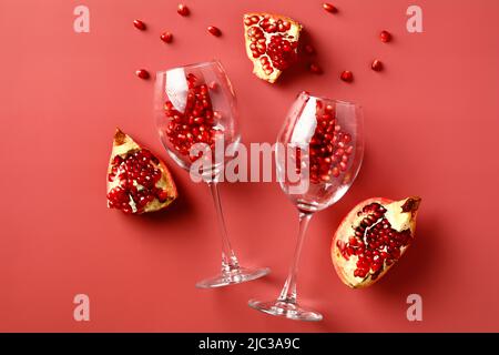 Weingläser mit Granatapfel auf rotem Hintergrund. Flach liegend, Draufsicht. Stockfoto