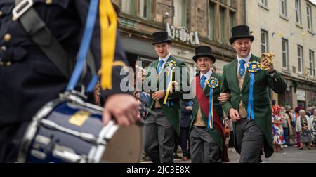 Hawick, Scottish Borders, Großbritannien. 9.. Juni 2022. VEREINIGTES KÖNIGREICH. UK Scotland News Hawick Common Riding kehrt 2022 nach der erzwungenen Lockdown-Pause von 19 zurück. Die Bilder zeigen einen der Schlüsselmomente des Wochenendes, als der Cornet, Greg Middlemas, ‘Center' flankiert von seinen linken und rechten Männern, entlang der Hawick High Street zum ‘Horse', einer Statue im Zentrum der Stadt, wo der Cornet, Klettert eine Leiter für die ‘Binden der Bänder' Zeremonie, wo blaue und goldene Bänder auf die Statue gebunden werden. Bildnachweis: phil wilkinson/Alamy Live News Stockfoto