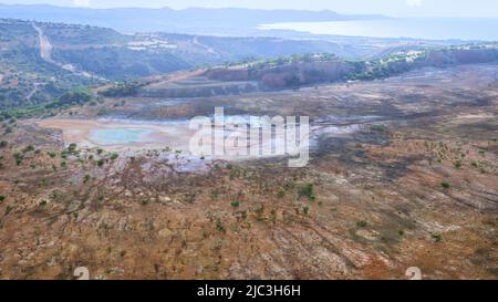 Verlassene Stätte der Kupfermine Limni, zyprische Luftlandschaft. Gefüllte offene Grube mit getrocknetem Pool und bunten Flecken von Chemikalien Stockfoto