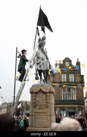 Hawick, Scottish Borders, Großbritannien. 9.. Juni 2022. VEREINIGTES KÖNIGREICH. UK Scotland News Hawick Common Riding kehrt 2022 nach der erzwungenen Lockdown-Pause von 19 zurück. Die Bilder zeigen einen der Schlüsselmomente des Wochenendes, als der Cornet, Greg Middlemas, ‘Center' flankiert von seinen linken und rechten Männern, entlang der Hawick High Street zum ‘Horse', einer Statue im Zentrum der Stadt, wo der Cornet, Klettert eine Leiter für die ‘Binden der Bänder' Zeremonie, wo blaue und goldene Bänder auf die Statue gebunden werden. Bildnachweis: phil wilkinson/Alamy Live News Stockfoto