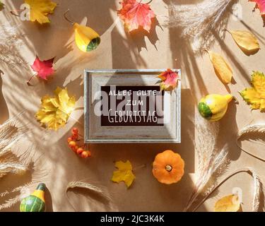 Text alles gute zum Geburtstag bedeutet auf Deutsch Alles Gute zum Geburtstag. Trockene Herbstblätter auf beigem Hintergrund. Stockfoto