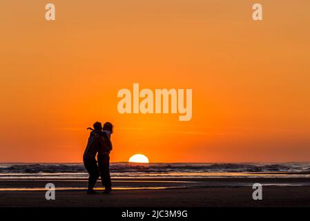 Silhouette eines Paares, das sich beim Sonnenuntergang am Strand küsst Stockfoto