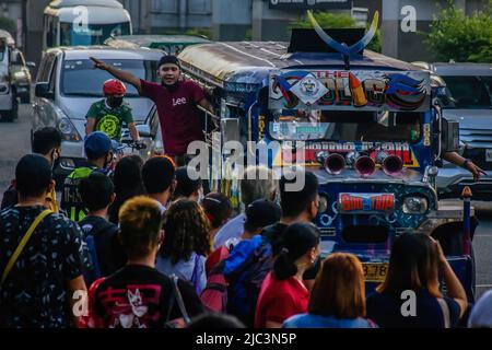 Quezon, Philippinen. 9.. Juni 2022. Pendler werden gesehen, wie sie auf den kommenden Jeep warten, der von einem Jeepney-Dispatcher bemannt wird. Dieselkraftstoff, der am häufigsten für Jeepneys (PUJ), einen Passagierjeep, verwendet wird, stieg auf fast 7 Pesos und erreichte 75 bis 87 philippinische Peso (1,45 bis 1,64USD) pro Liter, was zu einem Nettoanstieg auf 36 Pesos führte. Einige Jeepney-Fahrer halten ihre Fahrten aufgrund der fortandauernden Ölpreiserhöhungen immer noch an. (Bild: © Ryan Eduard Benaid/SOPA Images via ZUMA Press Wire) Stockfoto