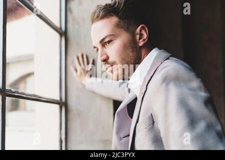 Besorgter junger Geschäftsmann aus der Zukunft schaut mit leerem Blick aus dem Fenster - Lifestyle-Konzept der Krise in Wirtschaft und Finanzen - Zukunft von y Stockfoto