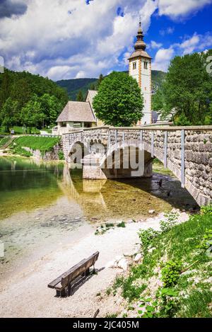 Bohinj See, Slowenien. Kirche des heiligen Johannes des Täufers mit Brücke über den Fluss Sava. Triglav Nationalpark in den Julischen Alpen. Stockfoto