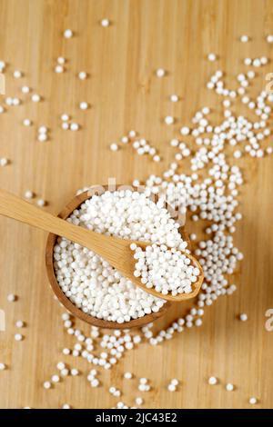 Draufsicht Haufenschal aus roher Sago-Perle auf Holzschale mit kleinem Holzlöffel Stockfoto