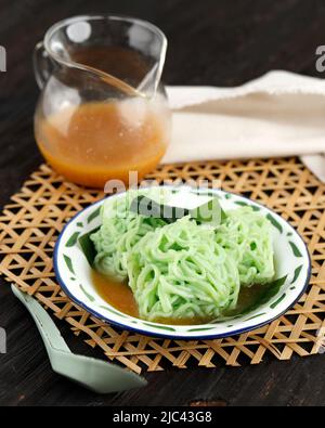 Putu Mayang oder Petulo, indonesischer traditioneller javanischer Snack aus Reismehlsträngen, zusammengerollt zu einem Ball mit Lebensmittelfarbe, serviert mit Kokosnuss Stockfoto