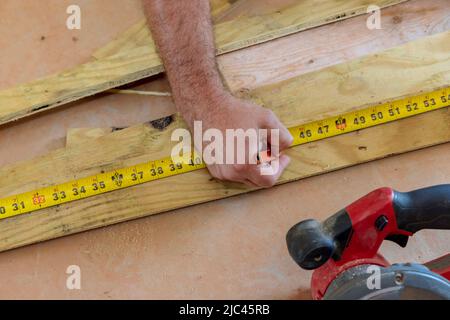 Zimmermann mit Bleistift in der Hand misst das Schneidebrett ein Maßband Stockfoto