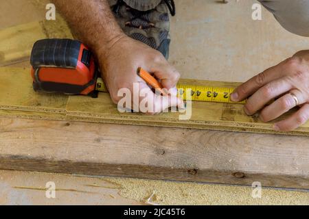 Ein Mann misst ein Stück Holz mit Maßband Stockfoto