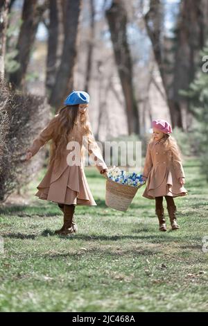 Zwei Mädchen Schwestern Kinder geht durch den Wald im Frühjahr und sammelt die ersten Frühlingsblumen in Korb . Stockfoto