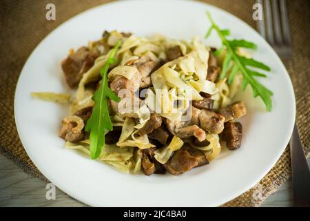 Hausgemachte gekochte Nudeln mit Fleisch und Auberginen auf einem Teller auf einem Holztisch Stockfoto