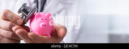 In der Nähe von einem Arzt Hand Kontrolle rosa Sparschwein mit Stethoskop Stockfoto