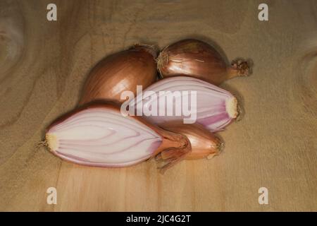 Halbgebackene Zwiebel (Allium cepa var. aggregatum), auf einem Holztisch, Food-Fotografie mit schwarzem Hintergrund Stockfoto