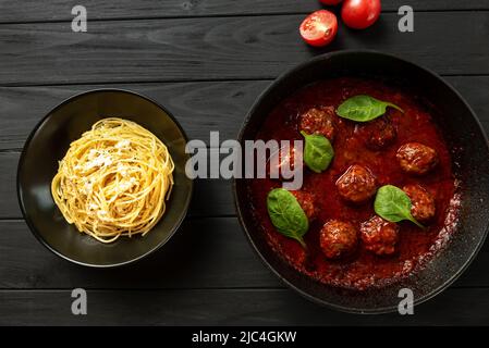 Der Prozess der Herstellung von italienischen Pasta mit Fleischbällchen. Ein Teller mit Spaghetti steht abseits der Fleischbällchen auf einem Grill auf dunklem Hintergrund Stockfoto