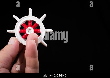 Lenkrad eines Bootes in der Hand auf schwarzem Hintergrund Stockfoto