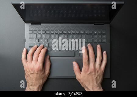 Tastatur für Laptop-Computer mit Benutzer- oder Gamer-Händen auf schwarzem, elegantem Hintergrund. Technologie, Business, Internet-Konzept. Hochwertige Fotos Stockfoto
