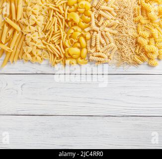 Verschiedene Arten und Formen italienischer Pasta auf weißem Holzhintergrund Stockfoto