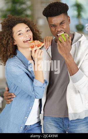 Frau, die eine Pizza isst und Mann, der in einen Apfel beißt Stockfoto