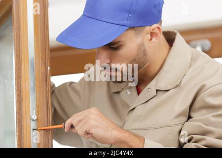 Ein Mann legt Grundlage Jalousien der Fenster zu Frame Stockfoto