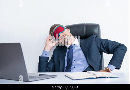 Müder Arbeitgeber entspannt sich in der Schlafmaske am Arbeitsplatz Stockfoto