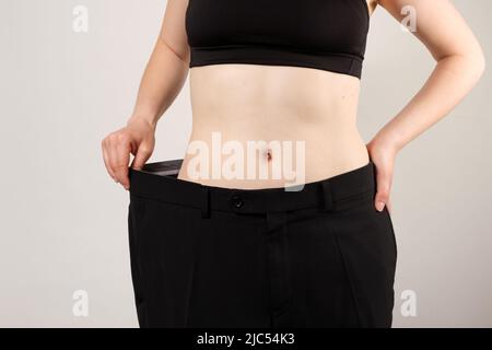 Eine Frau in großen Hosen nach dem Abnehmen, eine schöne weibliche Figur, das Konzept der Ernährung und gesunde Ernährung Stockfoto