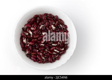 Rohe rote Kidney-Bohnen in weißer Keramikschale isoliert auf weißem Hintergrund, Bio-veganes Essen, Draufsicht Stockfoto