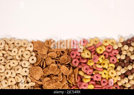 Eine Reihe verschiedener Frühstückscerealien - Ringe und Kugeln, Blick von oben auf weiß. Stockfoto