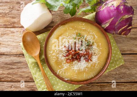 Hausgemachte, gesunde, pürierte Kohlrabi-Suppe mit Speck und Parmesankäse aus nächster Nähe in einer Schüssel auf dem Tisch. Horizontale Draufsicht von oben Stockfoto