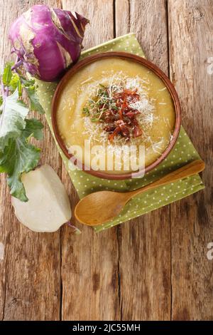 Cremige Kohlrabi-Suppe mit Speck und Parmesankäse in einer Schüssel auf dem Tisch. Vertikale Draufsicht von oben Stockfoto