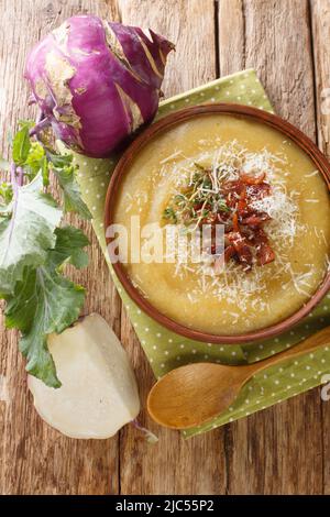 In einer Schüssel auf dem Tisch Kohlrabi- und Kartoffelsuppe mit Speck und Parmesankäse aus der Nähe pürieren. Vertikale Draufsicht von oben Stockfoto