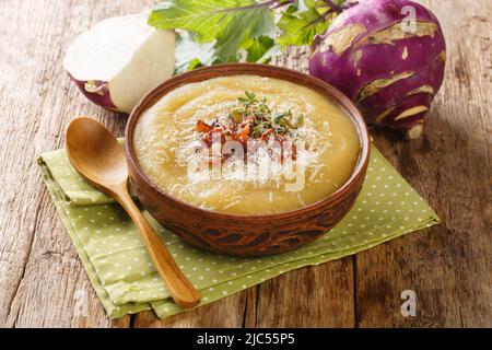 Cremig pürierte Kohlrabi-Suppe mit Speck und Parmesan in einer Schüssel auf dem Tisch. Horizontal Stockfoto