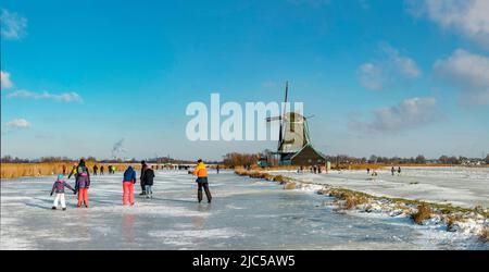 Scating auf einem gefrorenen Kanal in der Nähe einer Windmühle *** Local Caption *** Niederlande, Windmühle, Wasser, Winter, Schnee, Eis, Menschen, Scaters, ,Westzaan, Noord- Stockfoto