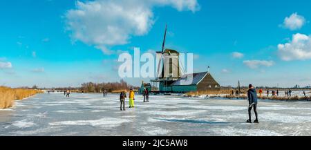 Scating auf einem gefrorenen Kanal in der Nähe einer Windmühle *** Local Caption *** Niederlande, Windmühle, Wasser, Winter, Schnee, Eis, Menschen, Scaters, ,Westzaan, Noord- Stockfoto