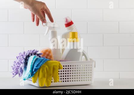 Die Hand einer Frau greift vor weißem Hintergrund nach Reinigungsprodukten für das Haus. Stockfoto