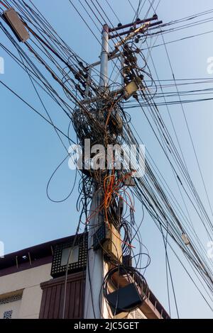 Strommasten mit überfüllten Drähten und Verteilerkasten in Indien. Stockfoto