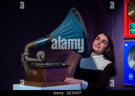 London, Großbritannien. 10.. Juni 2022. Ein Mitarbeiter mit einem „Vintage Horn Grammophon“, erste Hälfte des 20.. Jahrhunderts, (Est. £500-700), die sich im Home Office von John Peel bei der Vorschau von „Live in Session: Property from the John Peel Archive“ in Bonhams Knightsbridge befand. Artikel aus der Musiksammlung des verstorbenen John Peel, des BBC Radio DJ, Journalisten und Senders, werden am 14. Juni zum Verkauf angeboten. Kredit: Stephen Chung/Alamy Live Nachrichten Stockfoto