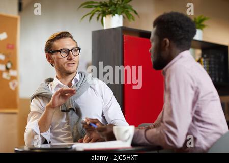 Moderne junge Business-Spezialisten sitzen im Open-Space-Büro und diskutieren Marketing-Projekt Stockfoto