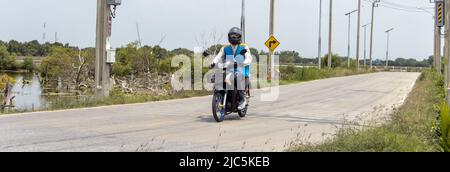 Der mototaxi-Fahrer in einer blauen Weste fährt auf der Landstraße Stockfoto