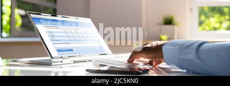 In der Nähe von einem Geschäftsmann Hand füllen Online Umfrage Formular auf Laptop Stockfoto