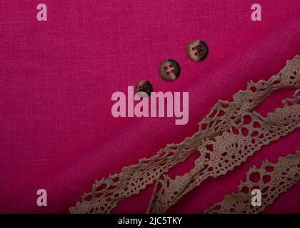 Hintergrund aus violettem Stoff, Knöpfe und Spitze. Fuchsia-Qualität. Pinkes Leinen für Kleidung Stockfoto