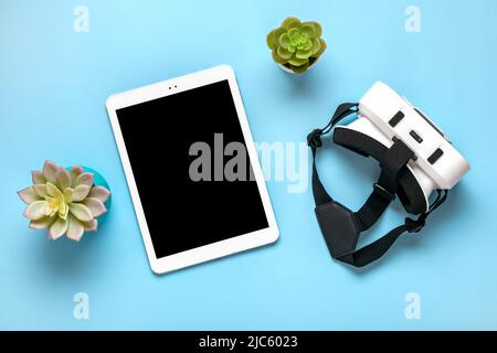 Weißes Tablet mit schwarzem Display, VR-Brille für Virtual-Reality-Spiele auf blauem Hintergrund Draufsicht Flat Lay Mock Up Technology Concept Platz zum Kopieren. Stockfoto