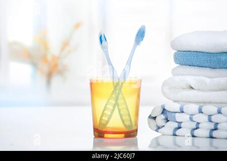 Zahnbürsten und Handtücher stapeln im Badezimmer.Tothbrush in Glas auf dem Tisch leere Kopie sapce. Stockfoto