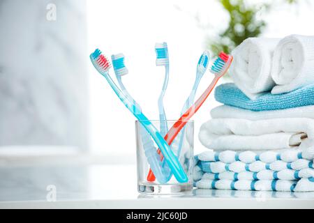 Zahnbürsten und Handtücher stapeln im Bad.Tothbrush auf Glas auf dem Tisch leere Kopie sapce.Hygiene. Stockfoto