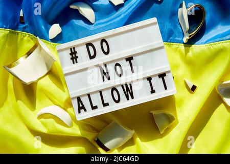 Ukrainische Flagge mit zerbrochenen Stücke von Cup: Symbol der Souveränität und nicht zulassen. Beenden Sie den Krieg in der Ukraine. Bleiben Sie in der Ukraine. Betet für die Ukraine. Stockfoto