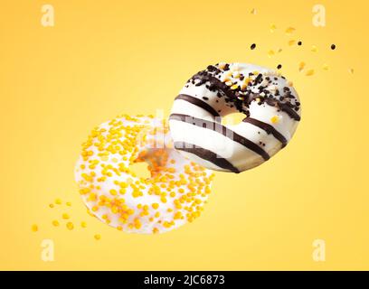 Donuts fliegen in der Luft auf gelbem Hintergrund.Bunte Donut fliegen.Süßes Dessert. Stockfoto