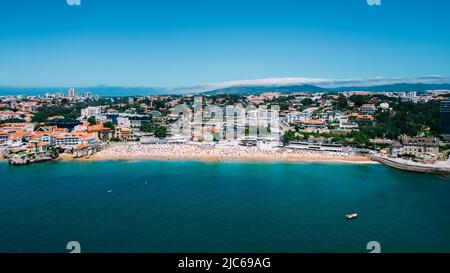 Drohnenaufnahme von nicht identifizierbaren Sonnenanbetern am Strand Praia da Conceicao in Cascais, Portugal Stockfoto